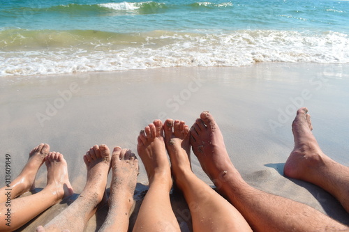 Feet on the beach. Family holidays by the sea. Tanned legs on the beach. Sitting together on the hot sand.