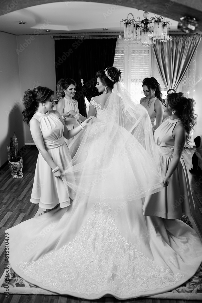  Gorgeous bride with her girlfriends posing in the room. Morning of beautiful bride. Happy girls at their best friend's wedding. Beautiful and elegant bride with bridesmaids.