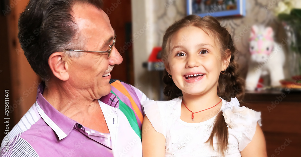 granddaughter hugging grandfather .photo on the background of children's room granddaughter hugging grandfather .photo on the background of children's room