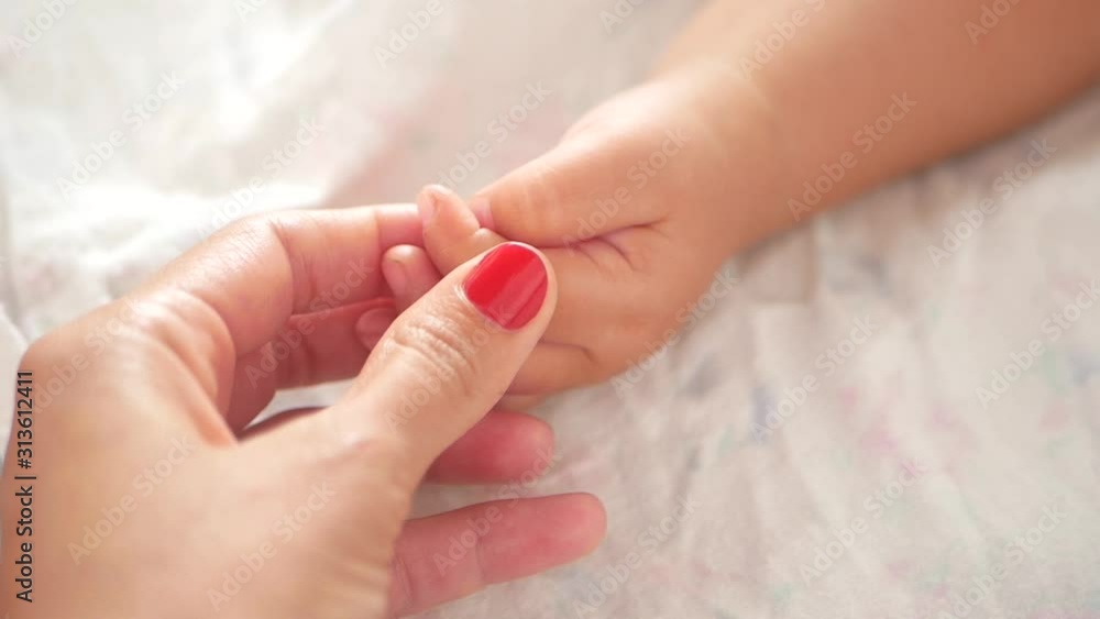 Mom strokes the hand of a newborn baby. Close-up of mom holding his baby fingers. mother strokes the finger of her newborn baby. the mother gently strokes the tiny little arms of her newborn baby. Chi Mom strokes the hand of a newborn baby. Close-up of mom holding his baby fingers. mother strokes the finger of her newborn baby. the mother gently strokes the tiny little arms of her newborn baby. Chi