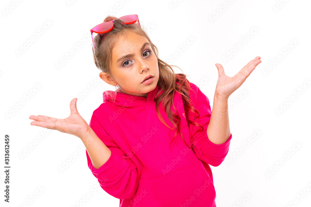 stylish girl in pink clothes gestures with displeasure and waves her arms to the sides on a white background
