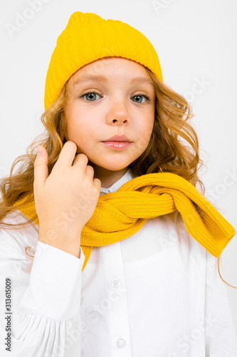 close-up portrait of an attractive girl in a yellow hat and white shirt with a sweatshirt tied over her shoulders photo