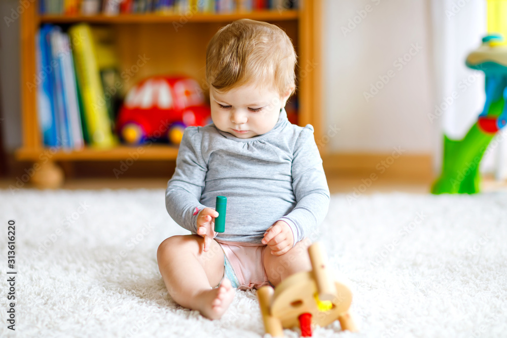Adorable baby girl playing with educational toys . Happy healthy child having fun with colorful different wooden toy at home. Early development for children with nature toy. Adorable baby girl playing with educational toys . Happy healthy child having fun with colorful different wooden toy at home. Early development for children with nature toy.