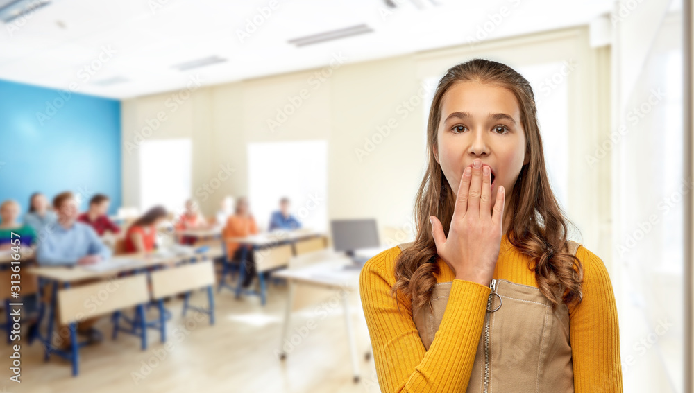 school, education and learning concept - scared or yawning teenage student girl closing her mouth by hand over classroom background school, education and learning concept - scared or yawning teenage student girl closing her mouth by hand over classroom background
