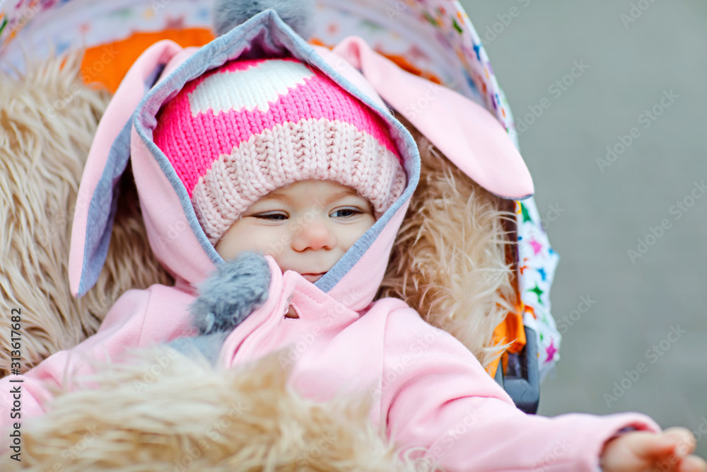 Cute little beautiful baby girl sitting in the pram or stroller on autumn day. Happy smiling child in warm clothes, fashion stylish baby coat. Healthy toddler going for walk on fresh air with parents Cute little beautiful baby girl sitting in the pram or stroller on autumn day. Happy smiling child in warm clothes, fashion stylish baby coat. Healthy toddler going for walk on fresh air with parents