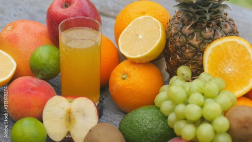 Close-up of a glass of fresh juice stands among many fruits on a wooden table. Fruit set. Healthy food concept. Breakfast. 4K UHD
