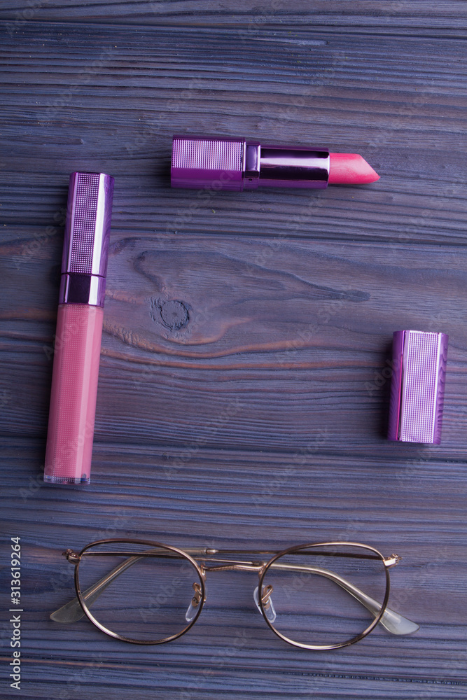 Fototapeta premium Red lipstic, mascara and glasses on wood. Flat lay, top view, copyspace, free space for text.
