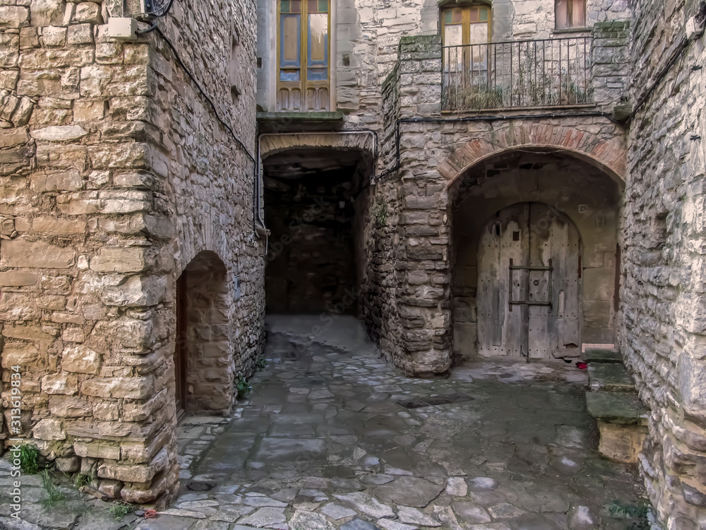 Spain, Montfalco Murallat - October 10, 2018: Old wooden gate in the stone walls of buildings in Montfalco Murallat village in Lleida province. Medieval houses with doors in a Spanish tourist place
