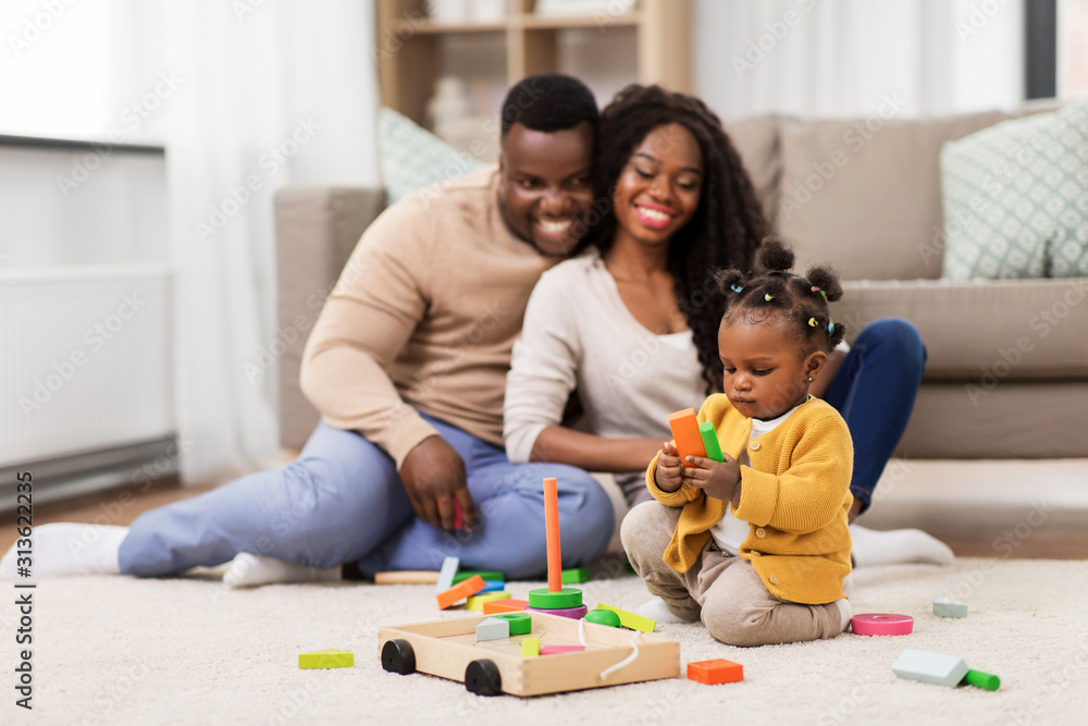 family, parenthood and people concept - happy african american mother, father and baby daughter playing with toy blocks at home family, parenthood and people concept - happy african american mother, father and baby daughter playing with toy blocks at home