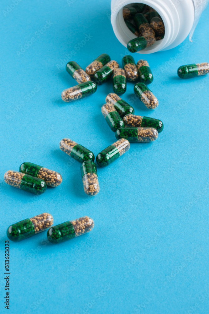 green-brown capsules of tablets or vitamins are scattered on a blue background. Medicine and health. green-brown capsules of tablets or vitamins are scattered on a blue background. Medicine and health.