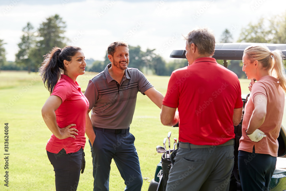 Group Of Male And Female Golfers Standing By Golf Buggy On Course Group Of Male And Female Golfers Standing By Golf Buggy On Course