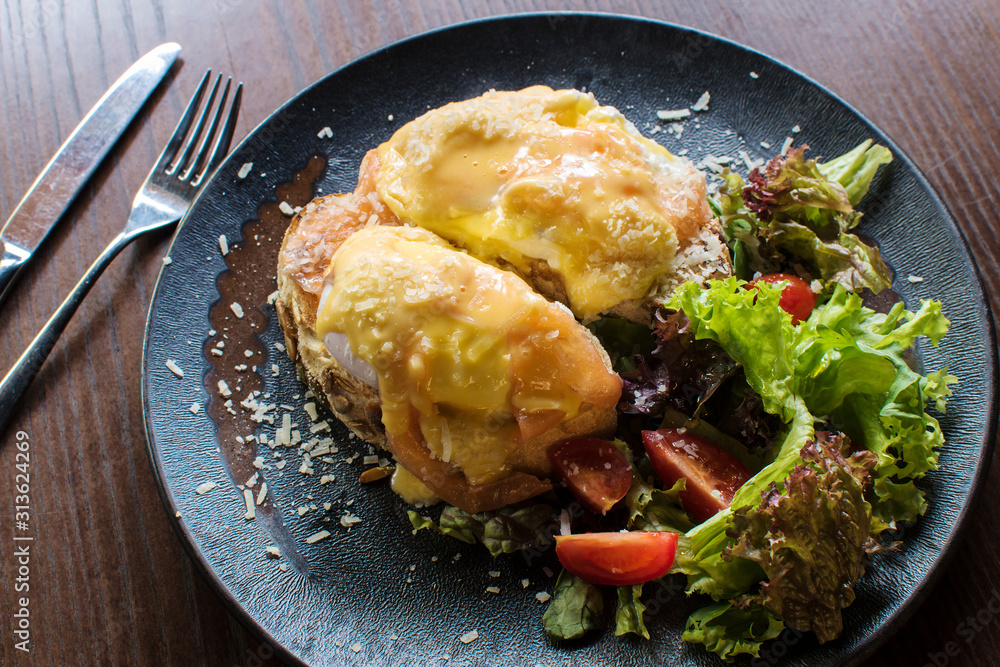 Top view of healthy breakfast with poached eggs royale, benedict with salmon and green salad on black Top view of healthy breakfast with poached eggs royale, benedict with salmon and green salad on black