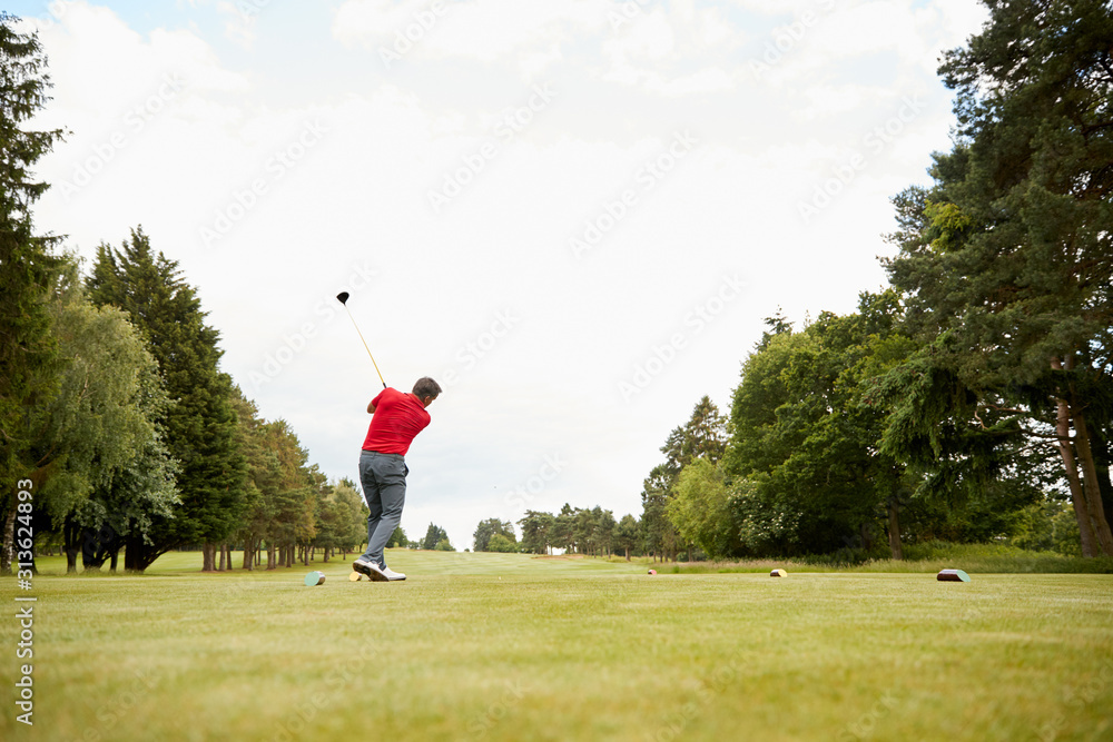 Mature Male Golfer Hitting Tee Shot Along Fairway With Driver Mature Male Golfer Hitting Tee Shot Along Fairway With Driver