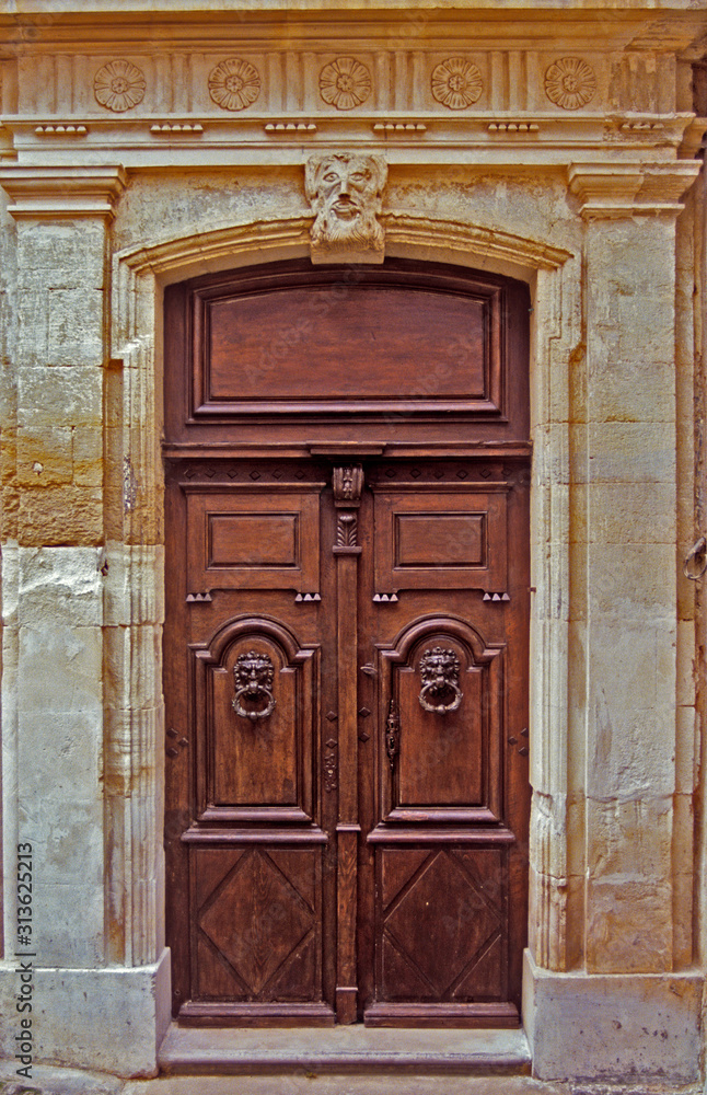 An old decorated wooden door with surrounding decorative classical stonework in Provence South of France An old decorated wooden door with surrounding decorative classical stonework in Provence South of France
