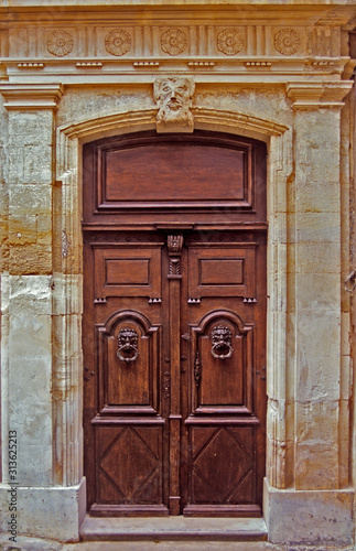 An old decorated wooden door with surrounding decorative classical stonework in Provence South of France