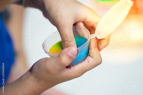 Kid hands play slime in container with flare