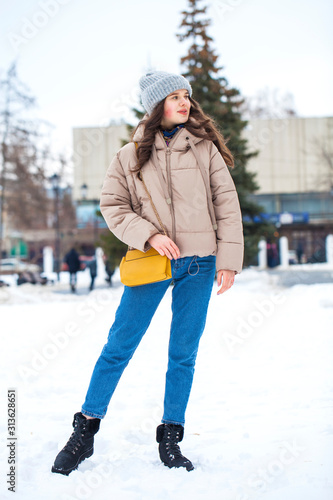 Portrait of young girl in blue jeans walking in a winter park