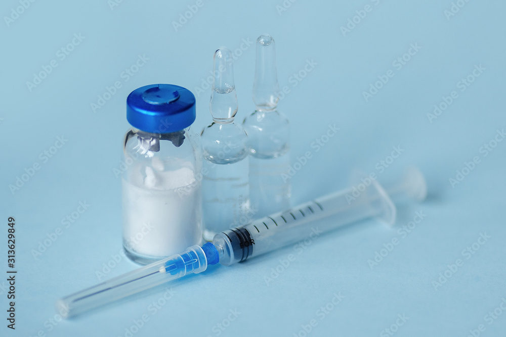 syringe and medicine in glass bottles on a blue background syringe and medicine in glass bottles on a blue background