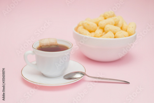 dessert, cup of tea with a bag, corn sticks, pink background