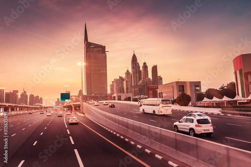 High speed highway road at sunset among high skyscrapers in downtown of Dubai city