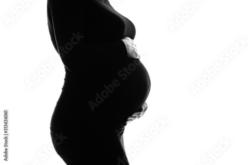 Femme enceinte en noir en studio avec les mains sur son ventre