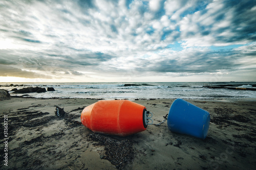 Red and blue buoys lie on the seashore