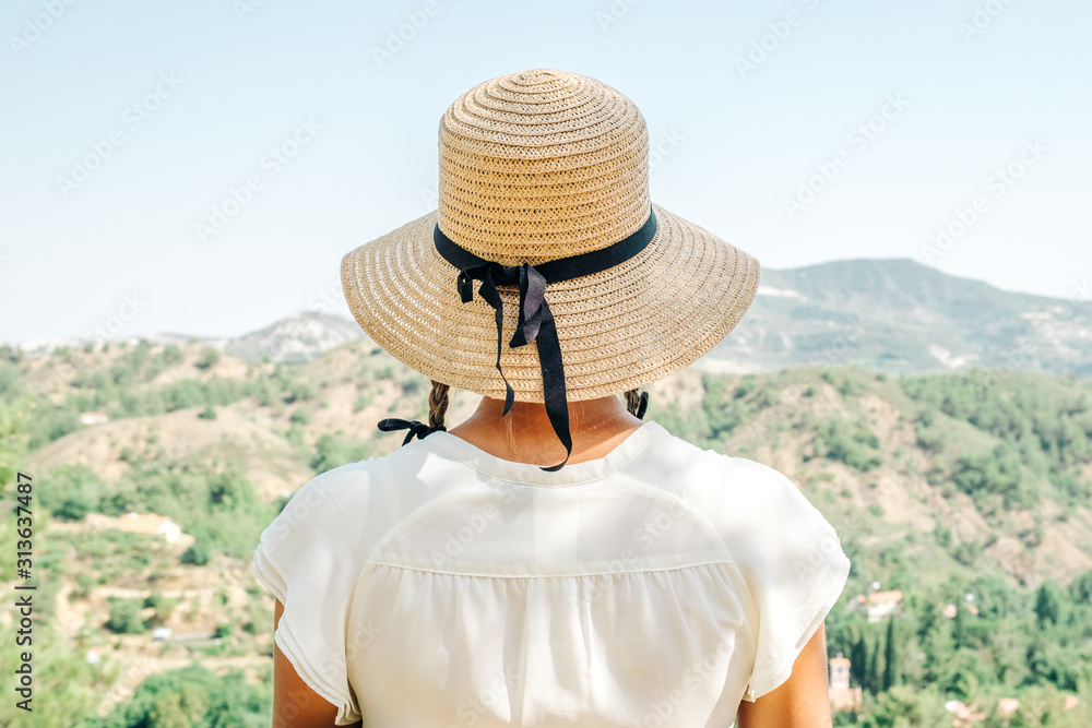 Beautiful woman wearing straw hat looking valley view