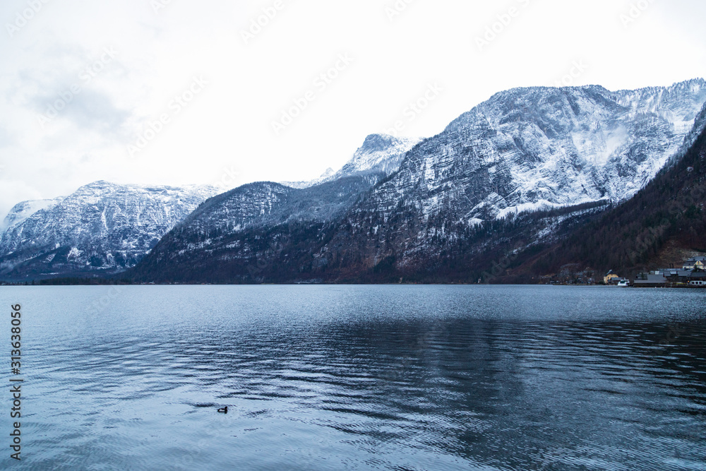 Winter lake surrounded by snow mountains of hallstatt in Austria.