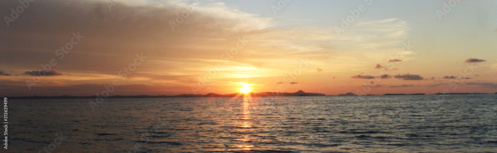 sunset at sea Panoramic View Of Beach Against Cloudy Sky - stock photo