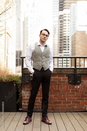 Fotografie Portrait of businessman wearing waistcoat with hands in pockets standing on hard