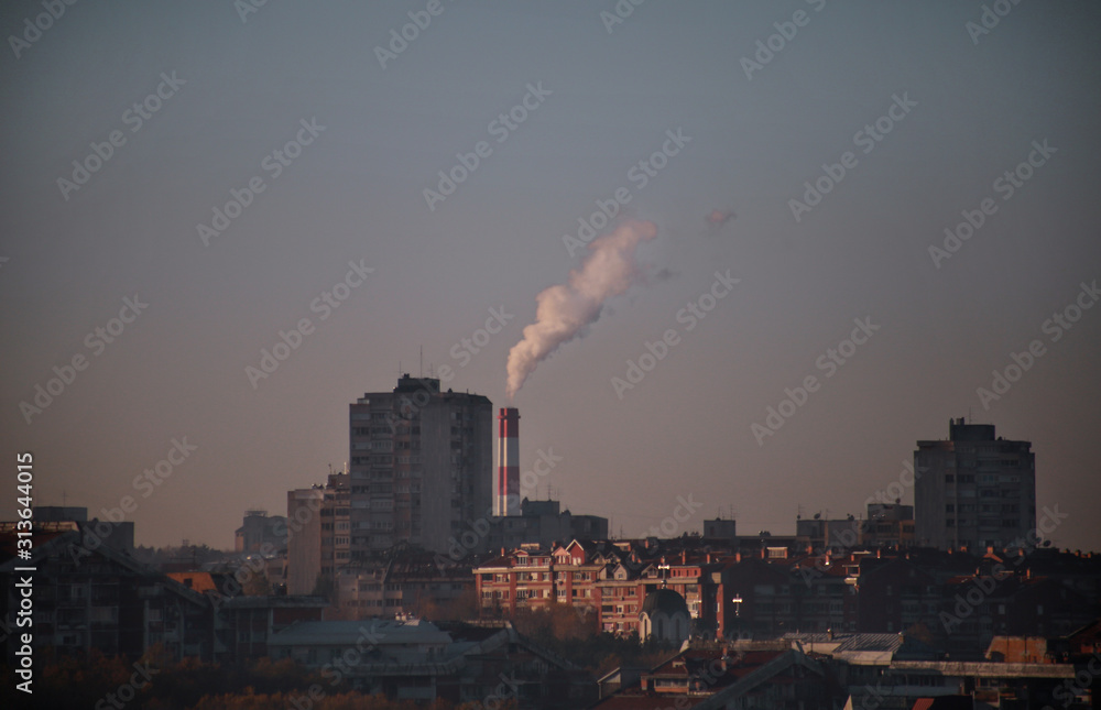 Smoking from industrial chimneys of heating plant emits smoke, smog at sunrise in city, pollutants enter atmosphere. Environmental disaster. Harmful emissions, exhaust gases into air. Heating season.
