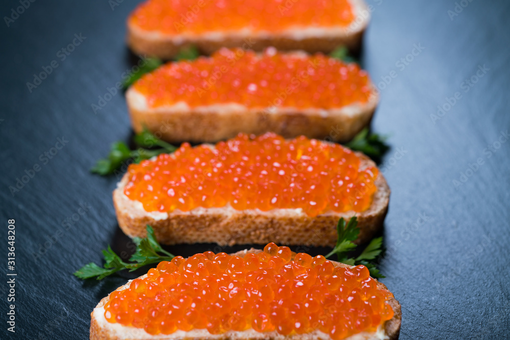 Sandwiches with red caviar on dark stone background Sandwiches with red caviar on dark stone background