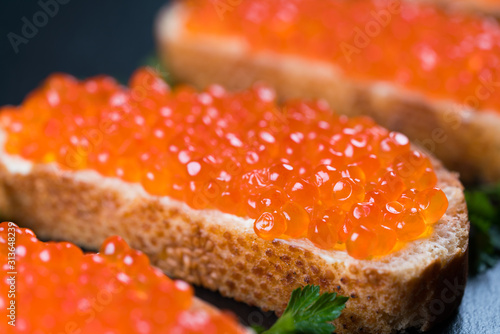 Sandwiches with red caviar on dark stone background