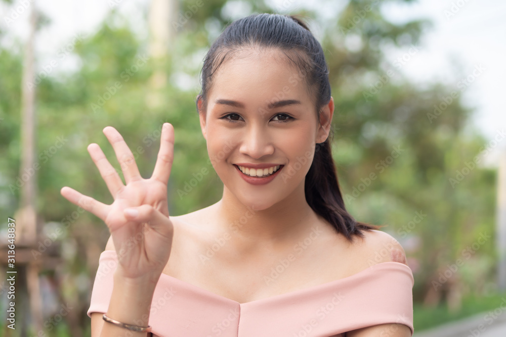 asian woman pointing, counting four finger; portrait of positive happy smiling asian woman pointing up 4 fingers for number four or 4 points concept ; southeast asian adult woman model, casual theme asian woman pointing, counting four finger; portrait of positive happy smiling asian woman pointing up 4 fingers for number four or 4 points concept ; southeast asian adult woman model, casual theme