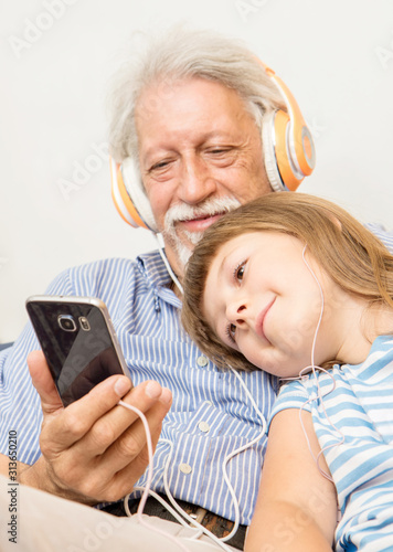 Foto grandfather and grandson with headphones listen to music hugging each other on t