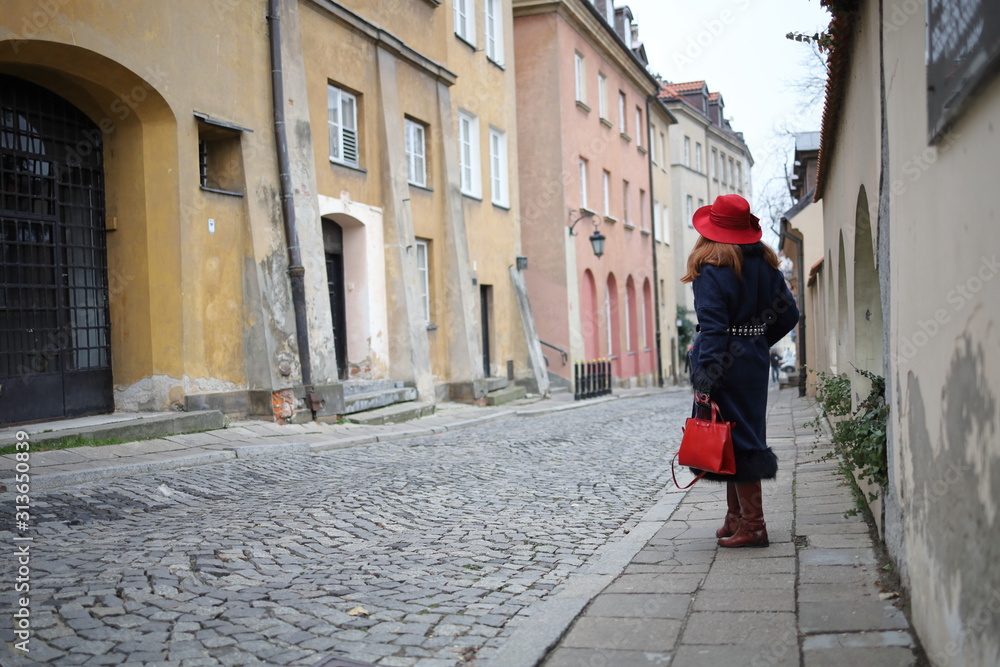 Elegant woman in a red hat in the old town of Warsaw.