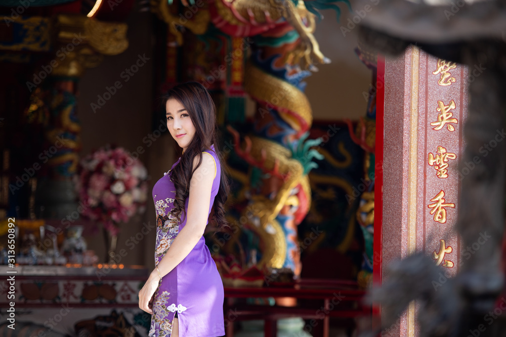 Portrait of Asian woman wearing purple cheongsam at chinese temple,Chinese New Year Festival.