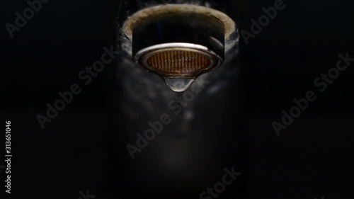 Bathroom tap leaking water drops, at night	