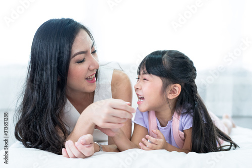 Mother and daughter playfully play on the bed. photo