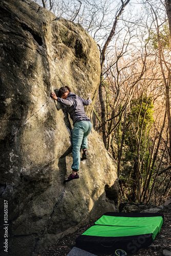 Woman bouldering in boulder area Varazze, Alpicella, Liguria, Italy