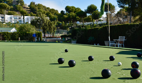 Lawn bowls balls positioned on a smooth playing surface, a bowls green.  photo