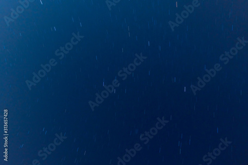 View to the moving stars at night, dark blue sky background. Long exposure shot. 