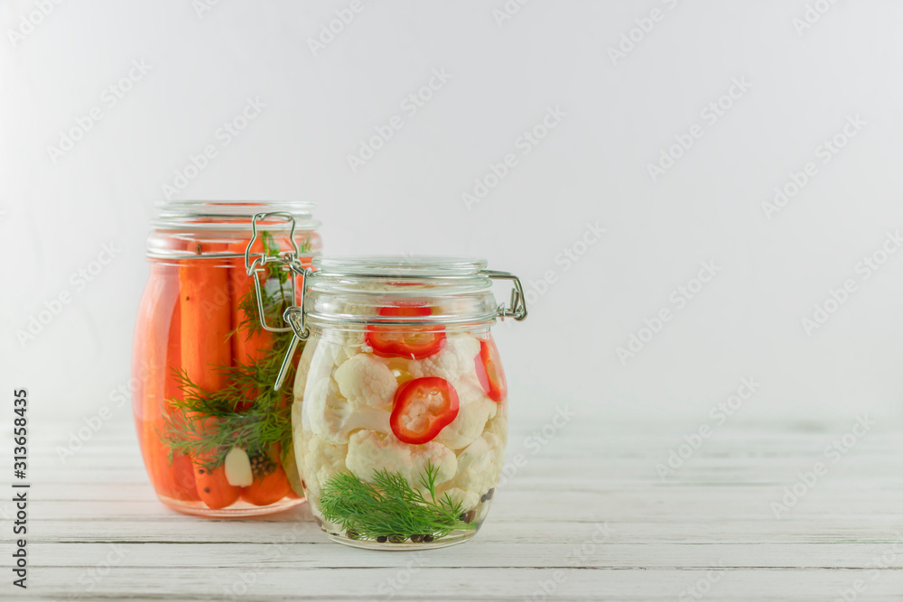 two glass jars of fermented cauliflower, carrots. vegetables on a light background. fermentation is a source of probiotic two glass jars of fermented cauliflower, carrots. vegetables on a light background. fermentation is a source of probiotic