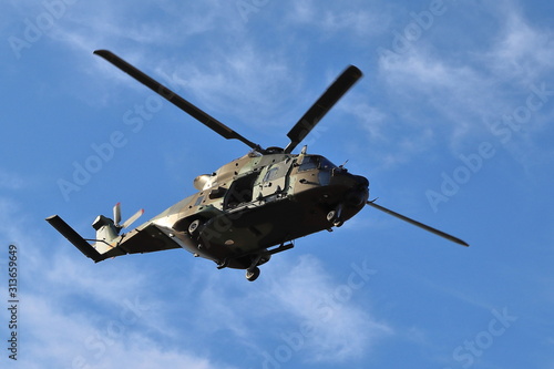 MILITARY HELICOPTER WITH A FOUR-BLADE ROTOR FLYING OVER AN AREA