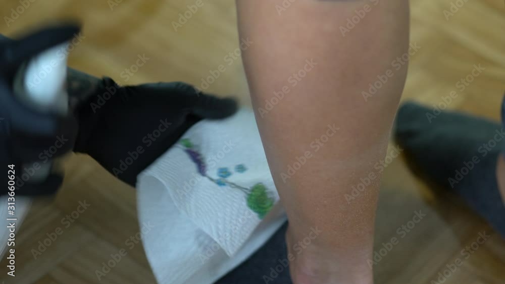 Tattoo female artist preparing costumers leg to make a tattoo Tattoo female artist preparing costumers leg to make a tattoo