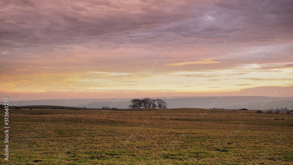Beautiful sunset lighting up the clouds over Danby Moor with lone trees set against the hills, North York Moors National Park, UK Beautiful sunset lighting up the clouds over Danby Moor with lone trees set against the hills, North York Moors National Park, UK