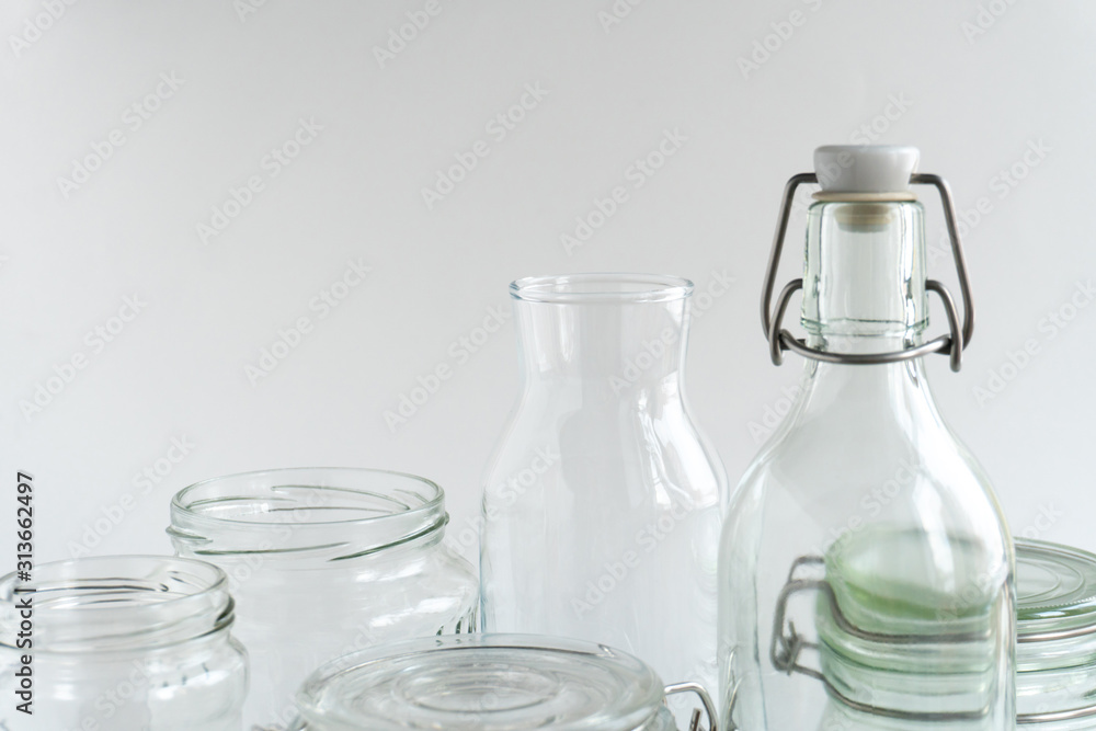 A variety of empty glass jars and bottles at white monochrome background. Zero waste concept. A variety of empty glass jars and bottles at white monochrome background. Zero waste concept.