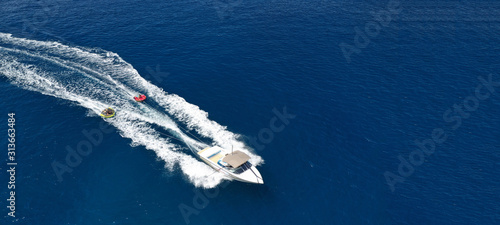 Aerial drone ultra wide photo of powerboat towing children having fun in donut water-sports © aerial-drone