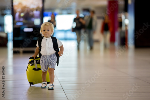 Sweet child, boy, walking at the airport, carrying suitcase and backpack