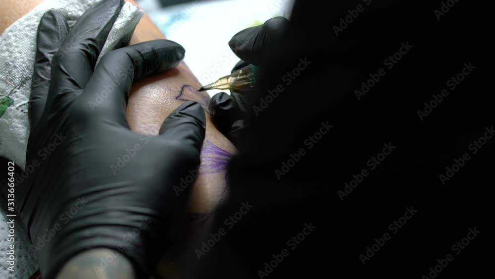 Tattoo female artist makes a tattoo on a female leg. Tattoo female artist makes a tattoo on a female leg.